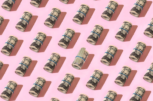Pattern of twenty dollar bill rolls on pastel pink background Dólar