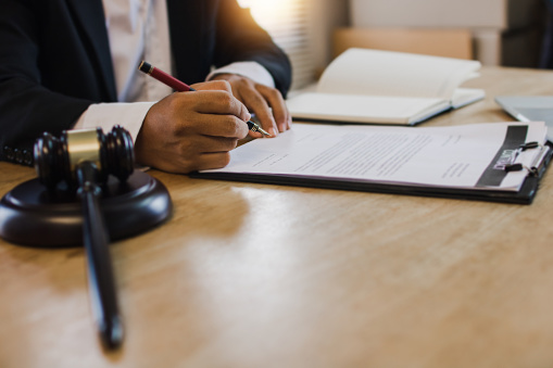 hand of business people sign contract with justice hummer on table tributarista